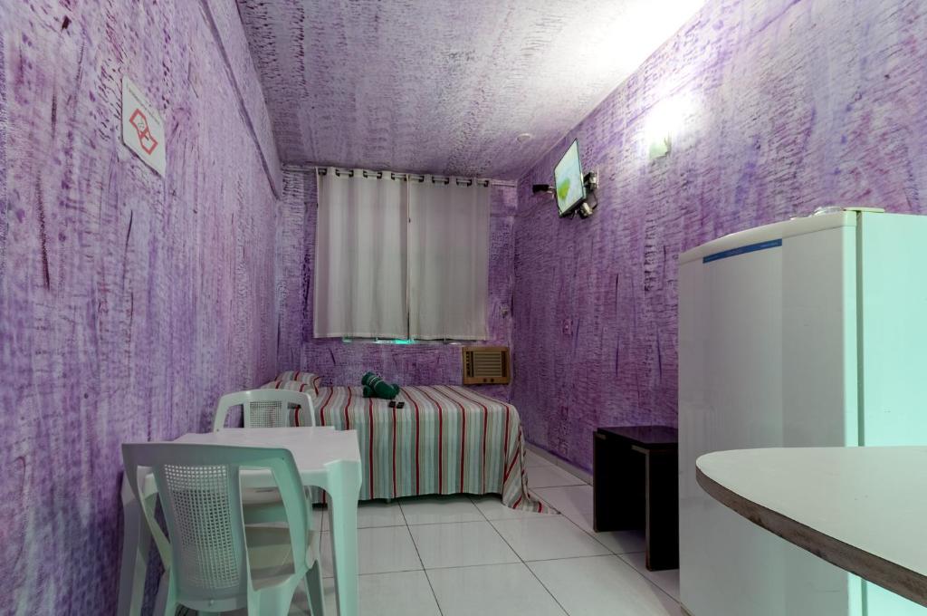 um quarto roxo com uma cama e um frigorífico em Pousada John John no Guarujá