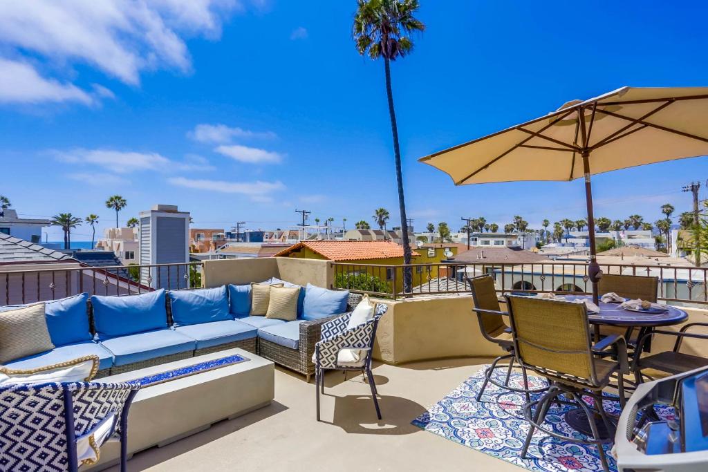 a patio with a couch and a table and an umbrella at Stunning Ocean View Home w Rooftop Terrace, Firepit, Fast Wifi, AC & Parking! in San Diego