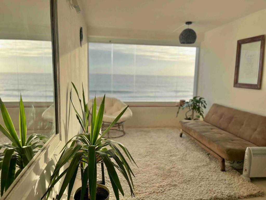sala de estar con sofá y vistas al océano en Departamento dúplex frente al mar en Reñaca en Viña del Mar