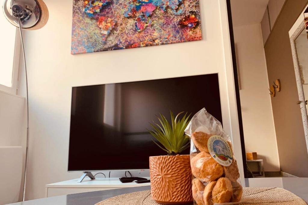 a living room with a television and a table with bread at "Chez Grâce" in Saintes