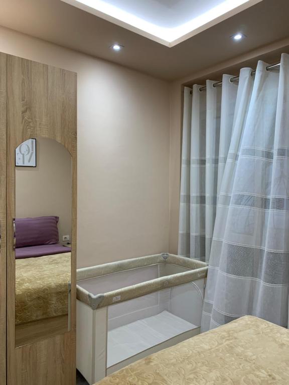 a bedroom with a bed and a mirror and a window at Ridi's Comfort Apartment in Shkodër