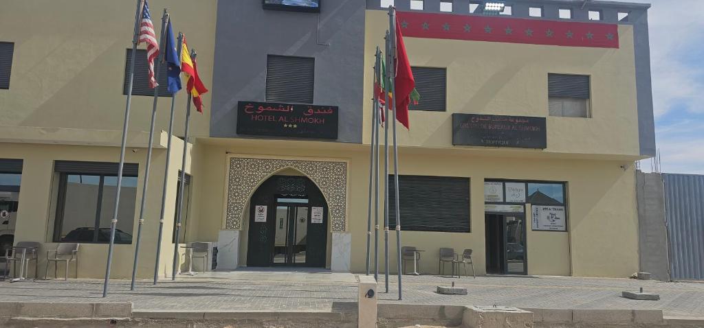 un bâtiment avec trois drapeaux devant lui dans l'établissement فندق الشموخ Hotel Al Shmokh, à Aousserd