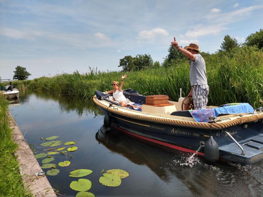 dos hombres en un barco en el agua en Het Waterhoentje, en Sint Jansklooster