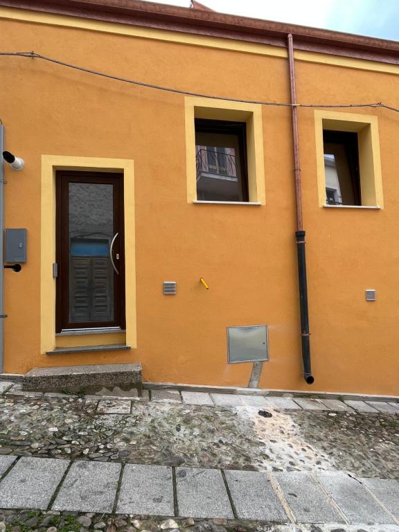 un edificio naranja con una puerta y dos ventanas en Sa domo de ziu Pedru, en Sennori