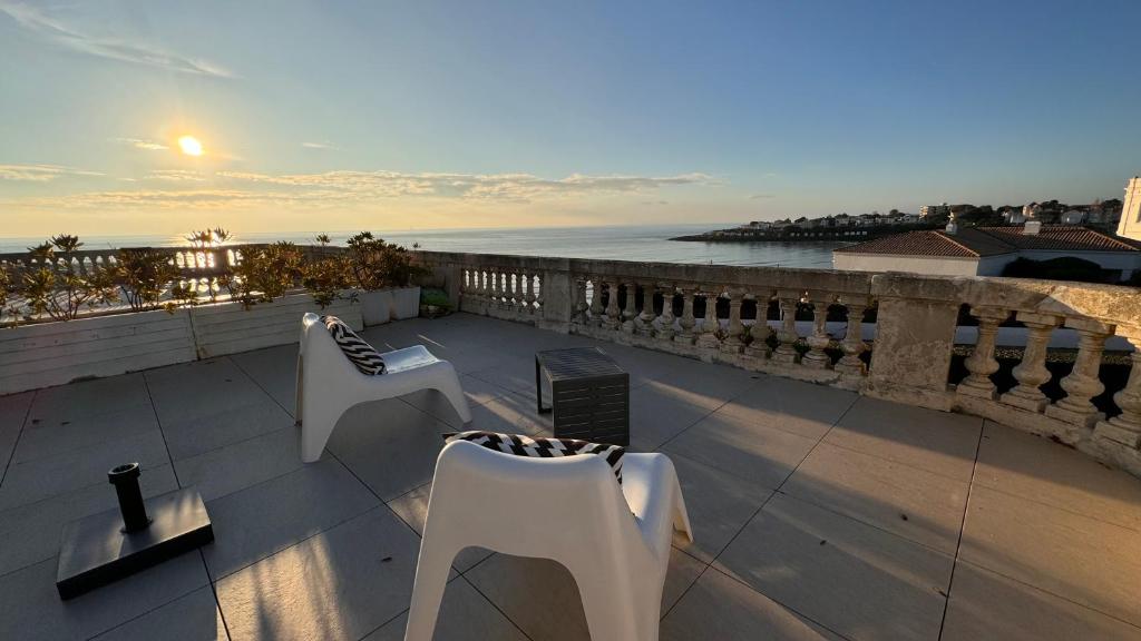 a balcony with two white chairs and a view of the ocean at Appartement vue mer à Pontaillac in Royan