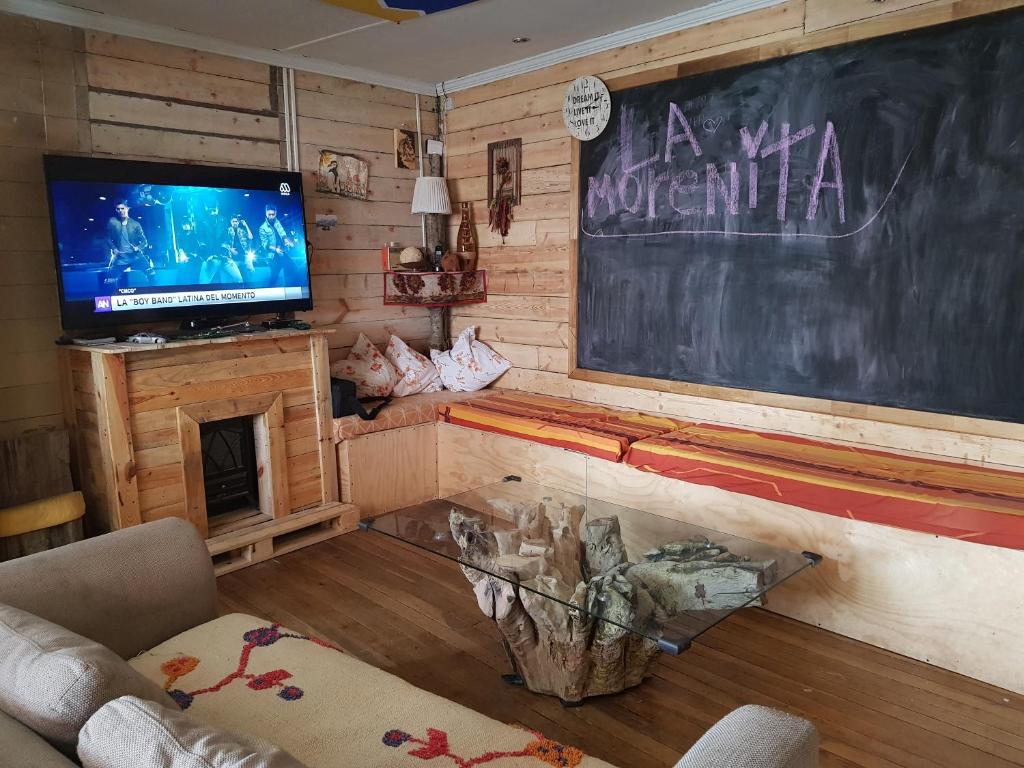 sala de estar con pizarra y TV en Hostel La Morenita, en Punta Arenas