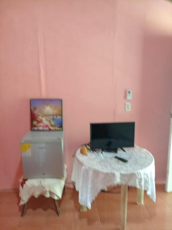 Hostal Ebenezer في Palmilla: غرفة وردية مع طاولة مع الكمبيوتر المحمول عليها