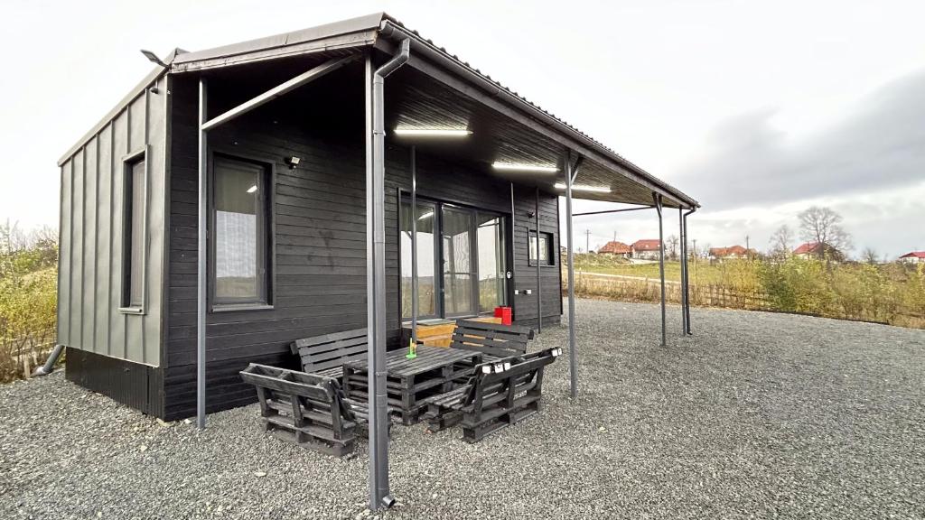 a small black cabin with benches in front of it at ATETA Tiny House 
