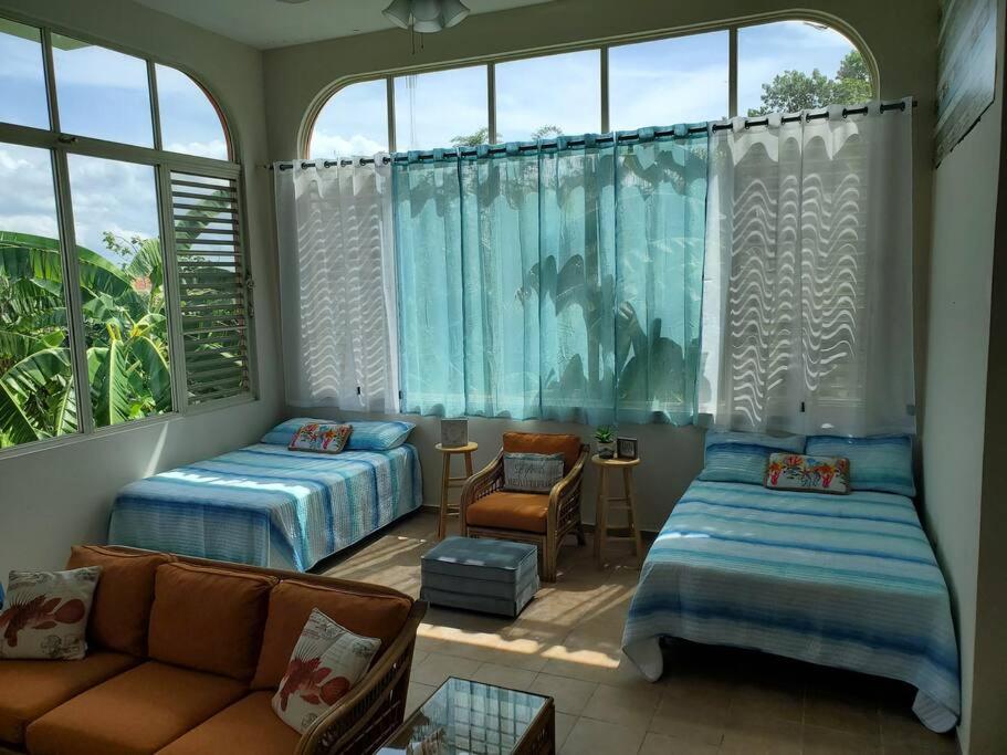 Cette chambre comprend deux lits, un canapé et une fenêtre. dans l'établissement NEW! Paradise at La Mela, à El Cerro