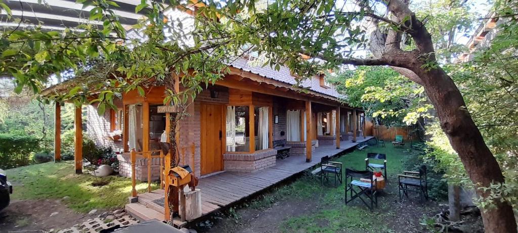 una veranda in legno di una casa con un albero di Santos Lugares Cabañas a Junín de los Andes