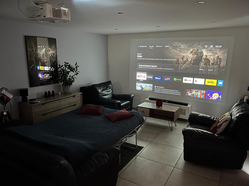 ein Wohnzimmer mit einem Sofa und einem großen Bildschirm in der Unterkunft Dépendance privative dans villa in Genay