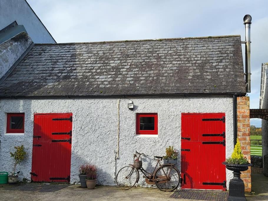 a bike parked in front of a white building with red doors at The Stable, Bennettsbridge, Kilkenny in Bennettsbridge