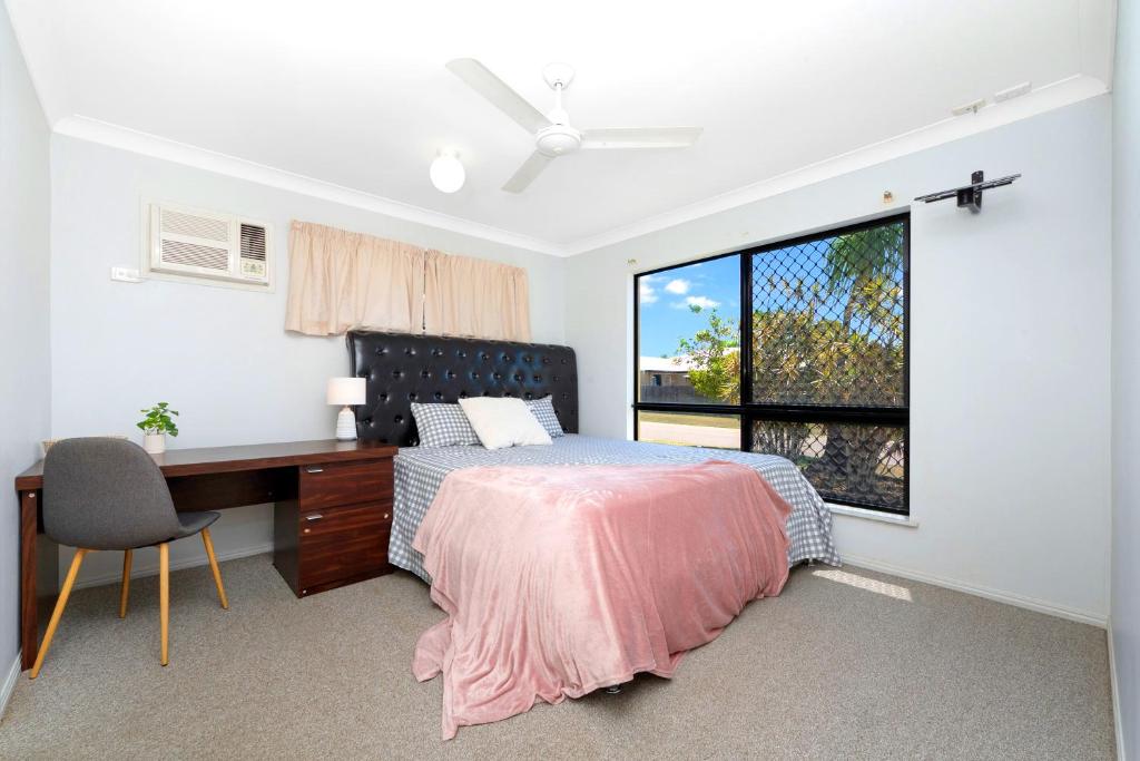 a bedroom with a desk and a bed and a window at Beautiful Home stay in Townsville in Rosslea