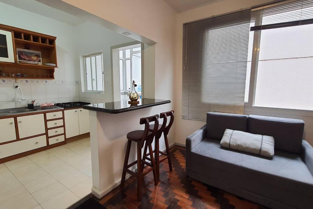 a kitchen with a bar and a couch in a room at 2 Dormitórios no Menino Deus ao lado do shopping Praia de Belas in Porto Alegre