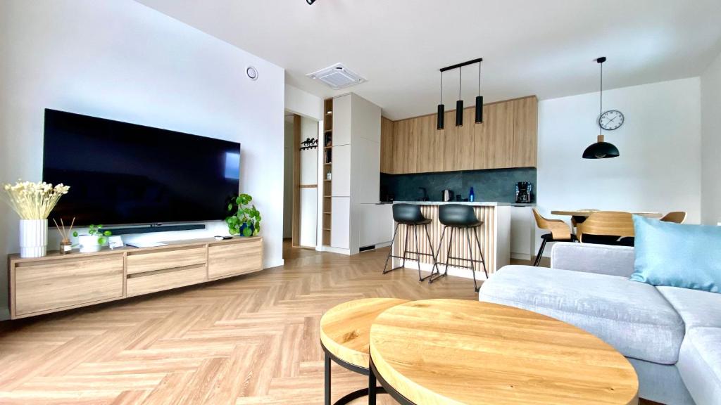ein Wohnzimmer mit einem Sofa, einem TV und einem Tisch in der Unterkunft ApartamentLesznoPL Family Friendly in Leszno
