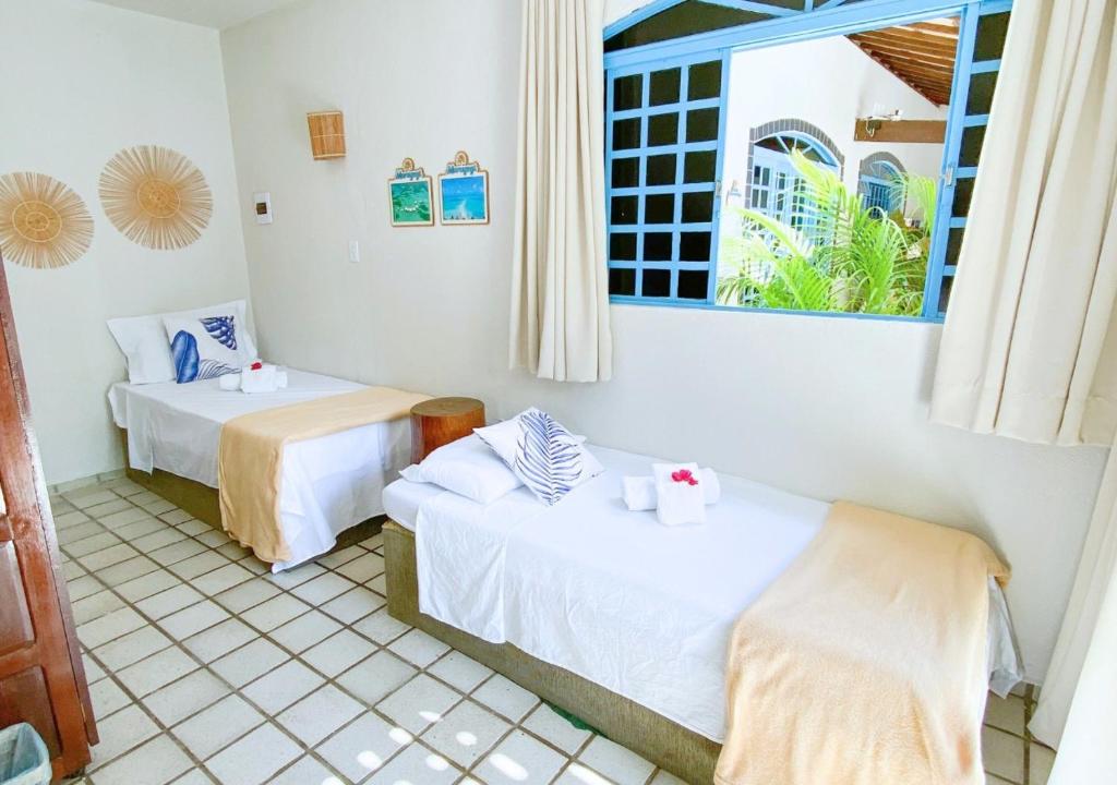 a room with two beds and a window at Pousada Praias do Norte in São Miguel dos Milagres