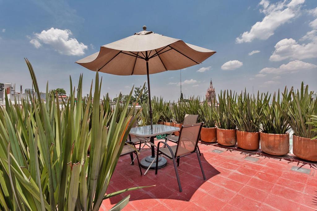 a table and chairs with an umbrella on a patio at Casas Artistas in San Miguel de Allende