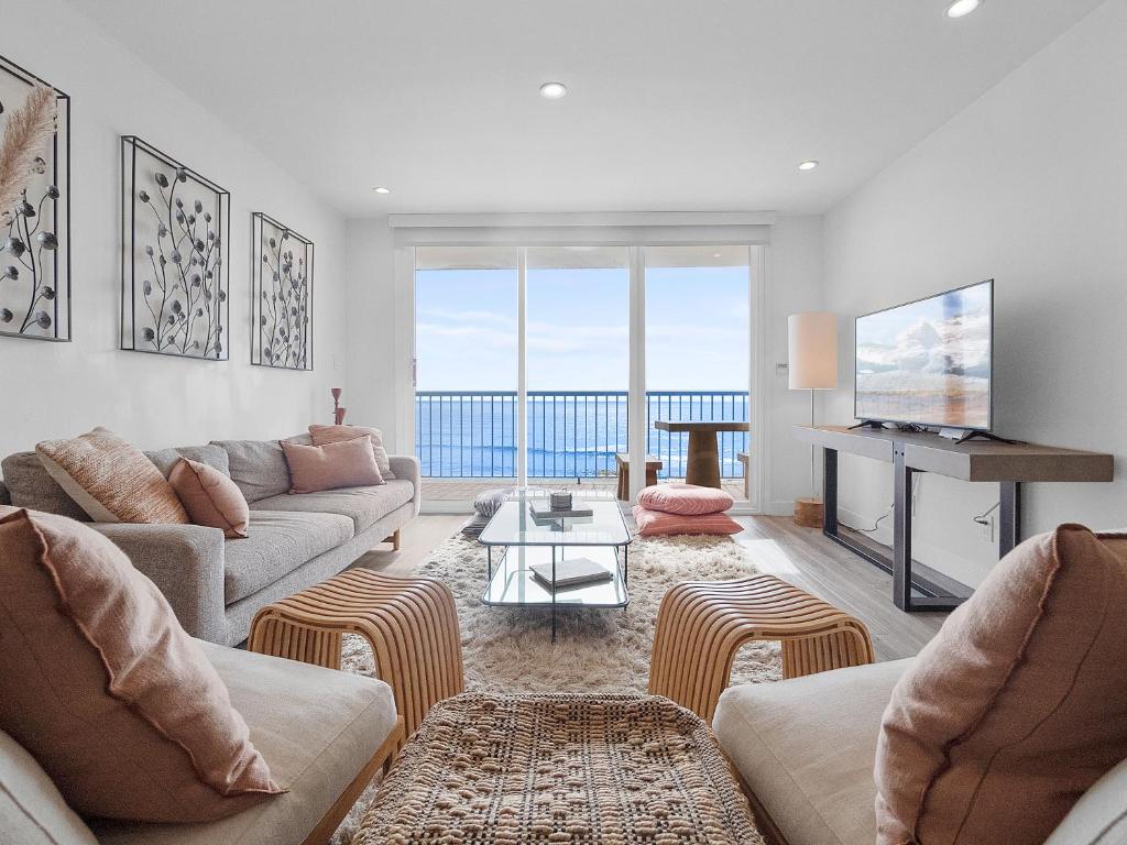 a living room with two couches and a television at Sunset Cliffs Lookout - Ocean Front Luxury Condo in San Diego