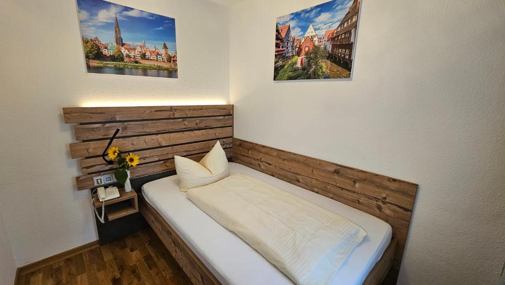 a small bed in a room with two pictures on the wall at Hotel Gasthof Rössle in Senden