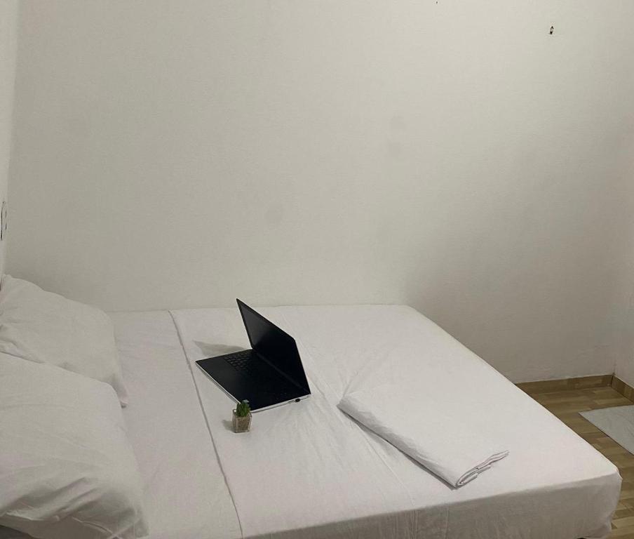 un computer portatile seduto sopra un letto bianco di Pousada manu a Trairi