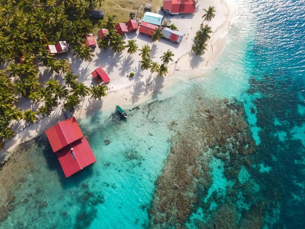 une vue aérienne sur une île avec des maisons rouges dans l'eau dans l'établissement Cabaña privada en Guna Yala isla diablo baño compartido, à Cagantupo
