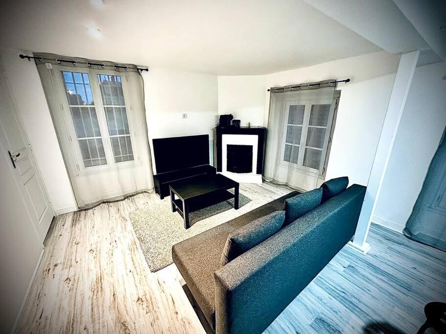 Appartement duplex à Chantilly centre في شانتيلي: غرفة معيشة مع أريكة زرقاء وطاولة