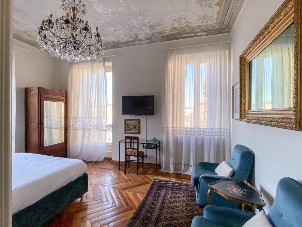 a bedroom with a bed and chairs and a chandelier at L'Angolo di Casa Verrua in Turin