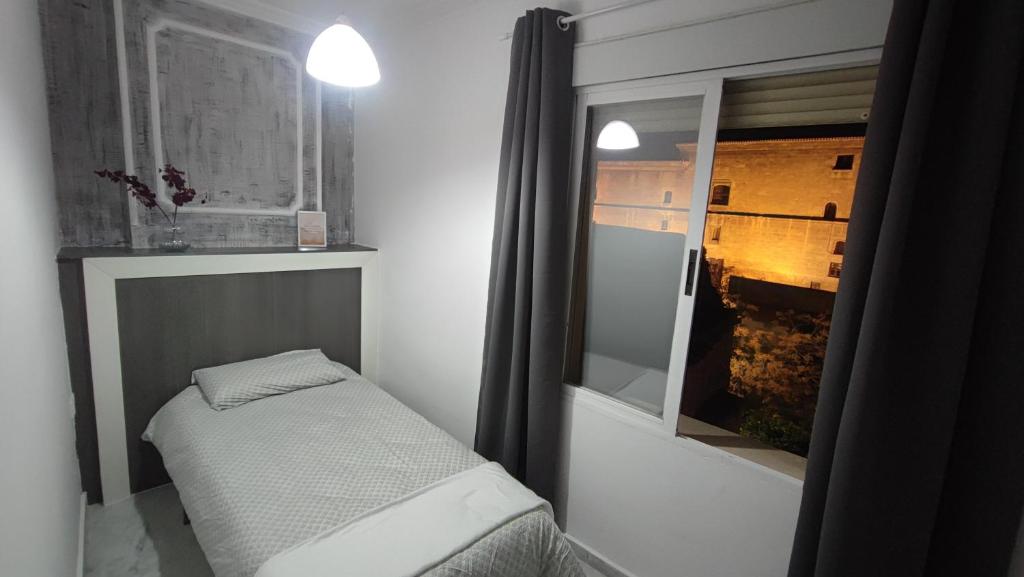 Habitación pequeña con cama y ventana en Vista Triunfo, en Granada