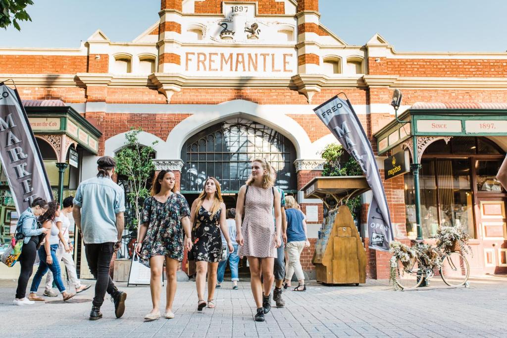 un groupe de personnes marchant dans une rue devant un bâtiment dans l'établissement Urban Studio, Steps From Fremantle's Heart, à Fremantle