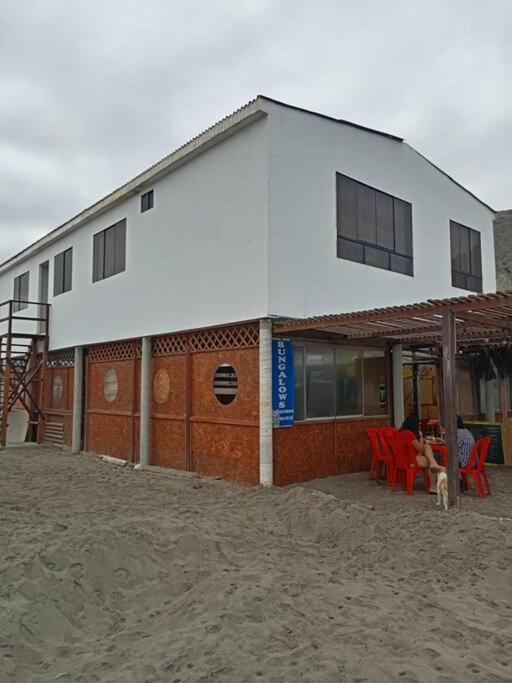 un edificio con mesas rojas y sillas delante de él en Hospedaje Rulos: Playa Yaya Las Salinas Chilca, en Salinas