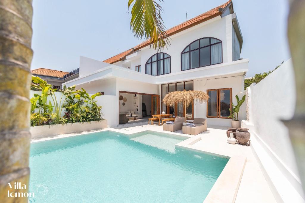 a villa with a swimming pool in front of a house at Beach Villas Canggu 300m from Echo Beach in Canggu