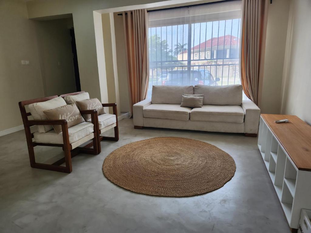 a living room with a couch and a chair and a large window at Graystone at Oyster Bay in Dar es Salaam
