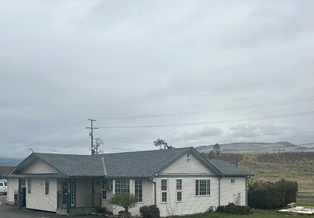 uma casa branca com uma porta verde num quintal em Road Runner Motel Merritt BC em Merritt