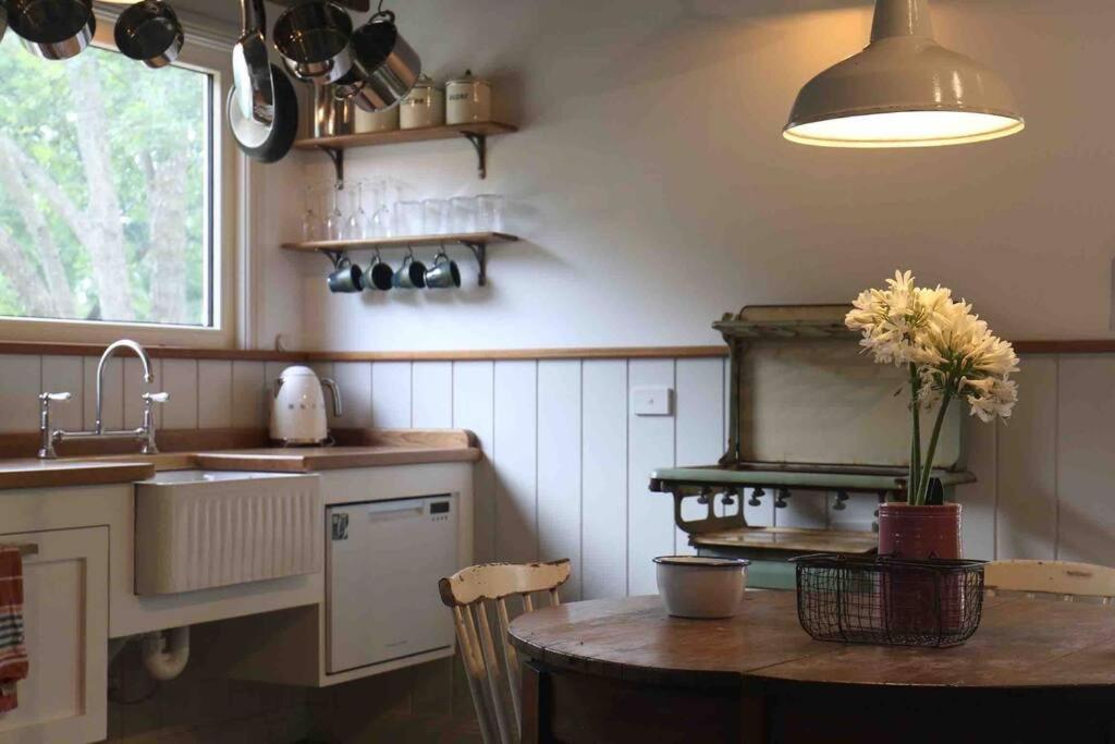 een keuken met een tafel, een wastafel en een fornuis bij The Pottery Shed in Boambee