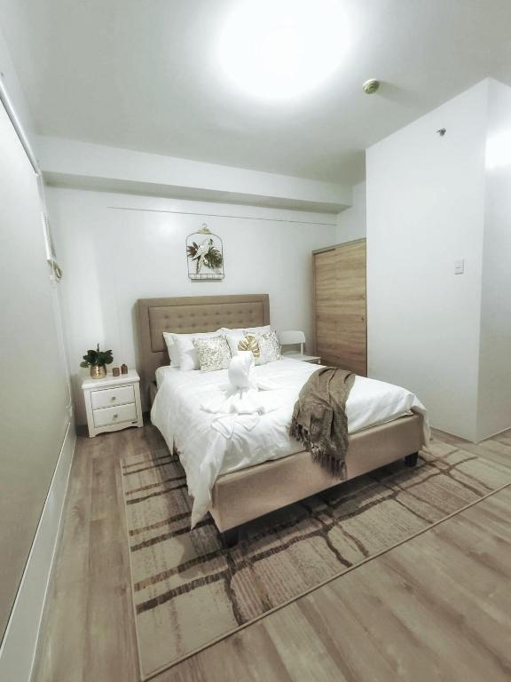 a bedroom with a large white bed and wooden floors at Minimalist Condo Studio at Messavire Garden Residence near Ruins Bacolod in Bacolod
