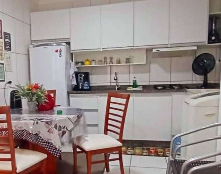 cocina con armarios blancos, mesa y sillas en Aconchegante apto, quadra do mar, no Tabuleiro! en Barra Velha