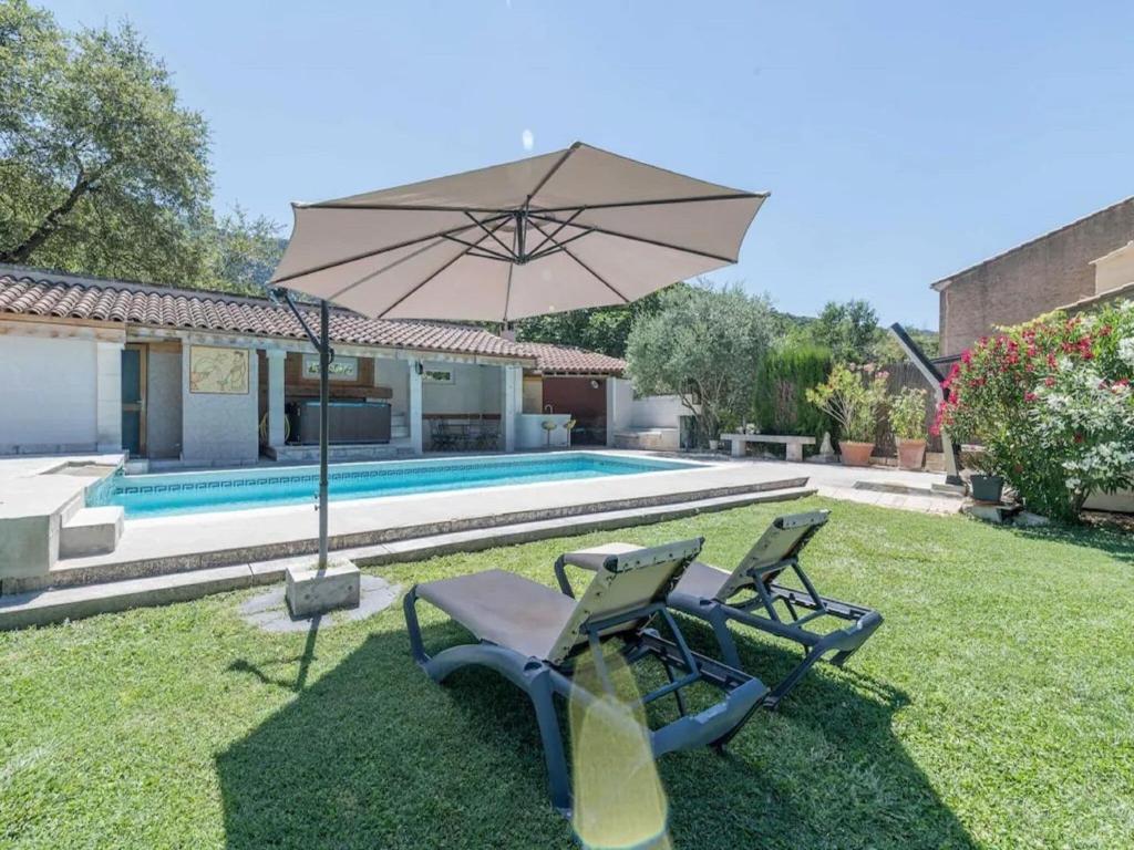 a yard with two chairs and an umbrella next to a pool at Villa with swimming pool within the Luberon in Oppède