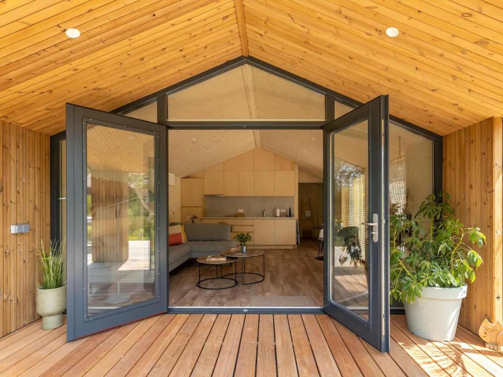 een open glazen deur op een terras met planten bij Nature house on a beautiful and green domain in Kortgene