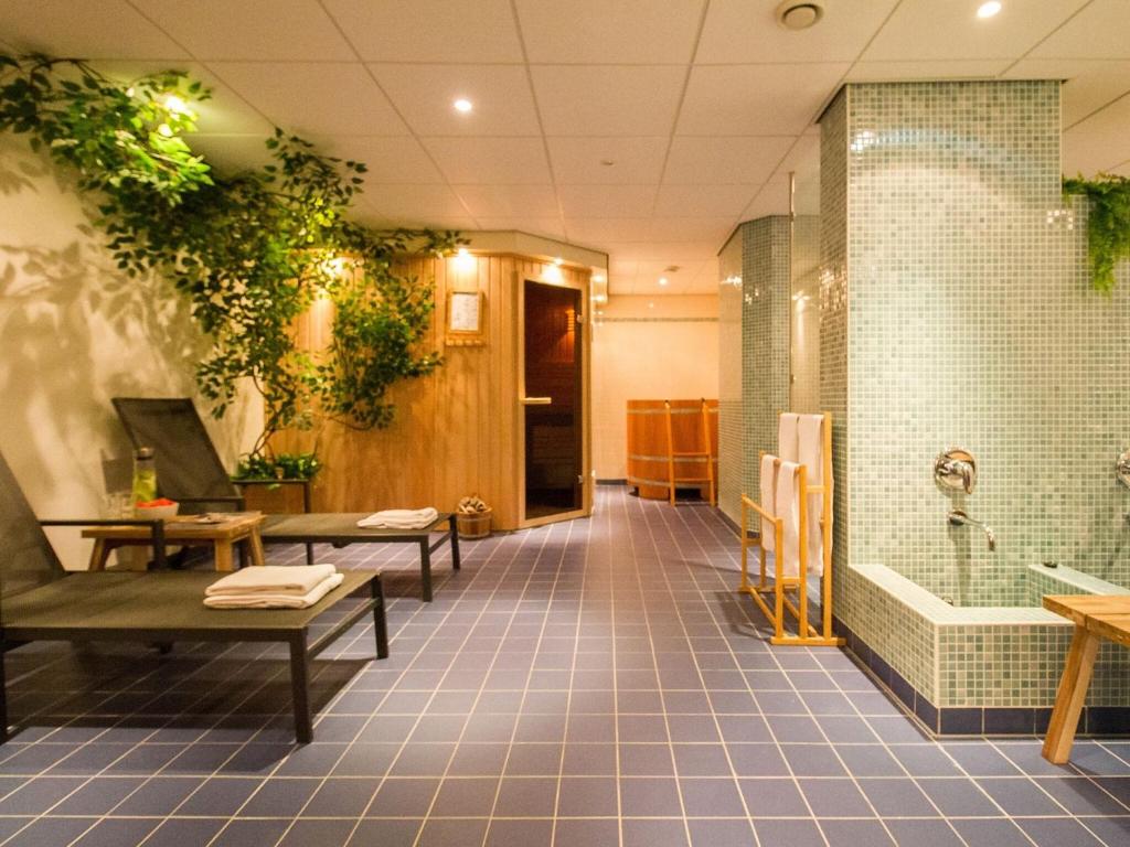 ein Bad mit einer Dusche und einer Badewanne mit Pflanzen in der Unterkunft Beautiful holiday home in Voorthuizen in a wonderful setting in Voorthuizen