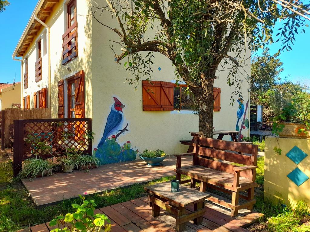 un banco de madera sentado frente a una casa con un mural en Complejo Sol de Valizas en Barra de Valizas