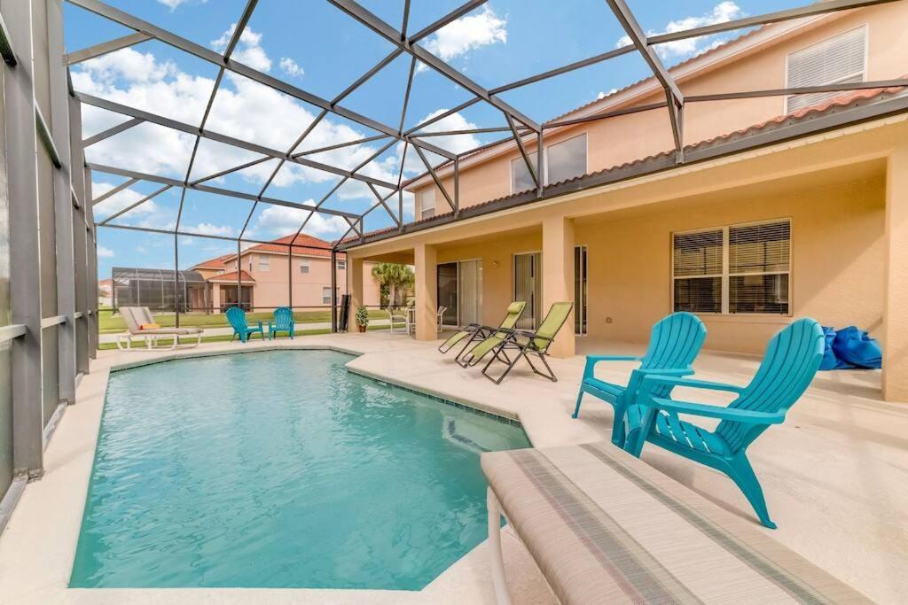 basen z 2 niebieskimi krzesłami i dom w obiekcie Family Pool Home, Gated Resort, near Disney & golf -209 w Orlando