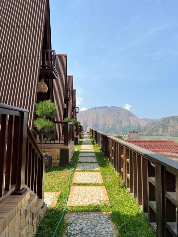 una pasarela entre dos edificios con montañas en el fondo en HK VILLA'S, en Sembalun Lawang