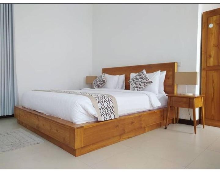 - un grand lit avec un cadre en bois dans une chambre dans l'établissement VilaDewaScaAcomodation, à Ubud