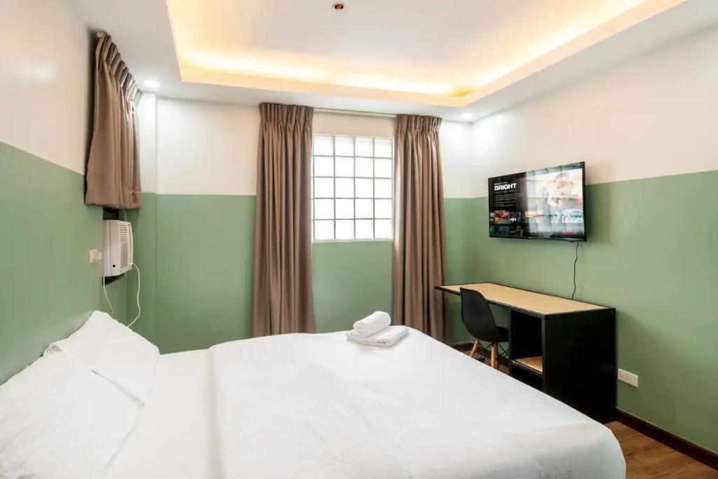 Dormitorio con cama, escritorio y TV en St. Marvin Studio Makati M507, en Manila
