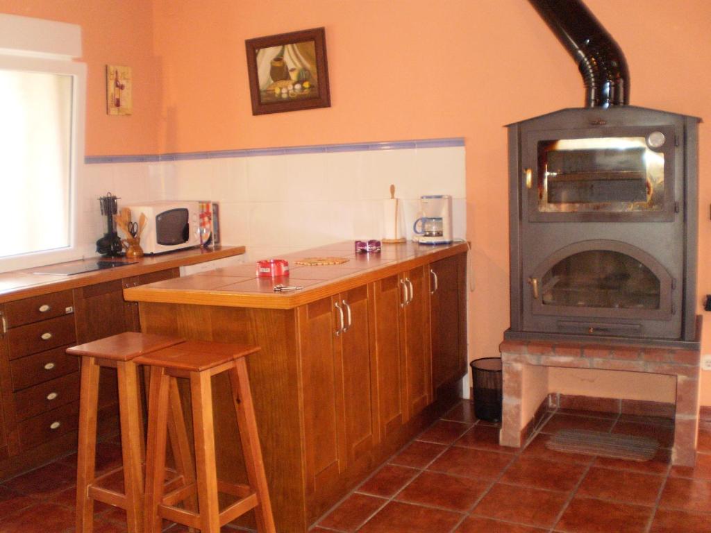 a kitchen with a stove and a counter with stools at Los Olmos Holiday Home in Fuentidueña