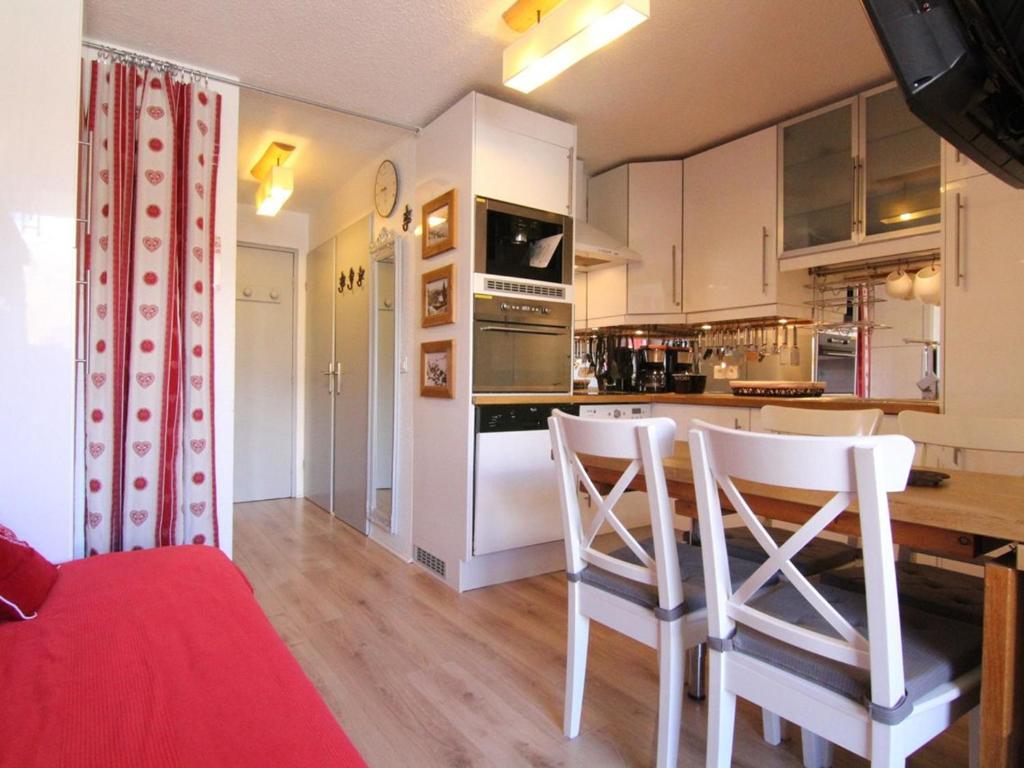 eine Küche mit weißen Schränken sowie einem Tisch und Stühlen in der Unterkunft Appartement Huez, 2 pièces, 5 personnes - FR-1-405-341 in Huez