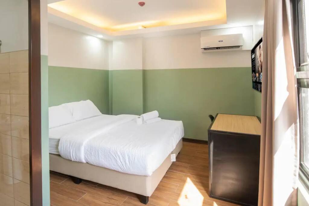 ein Schlafzimmer mit einem weißen Bett und grünen Wänden in der Unterkunft St. Marvin Studio Makati M506 in Manila