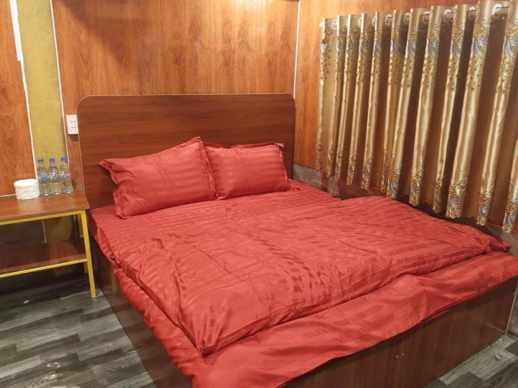 - un lit avec des draps rouges et une tête de lit en bois dans l'établissement Hải Đăng Homestay, à Loung Co