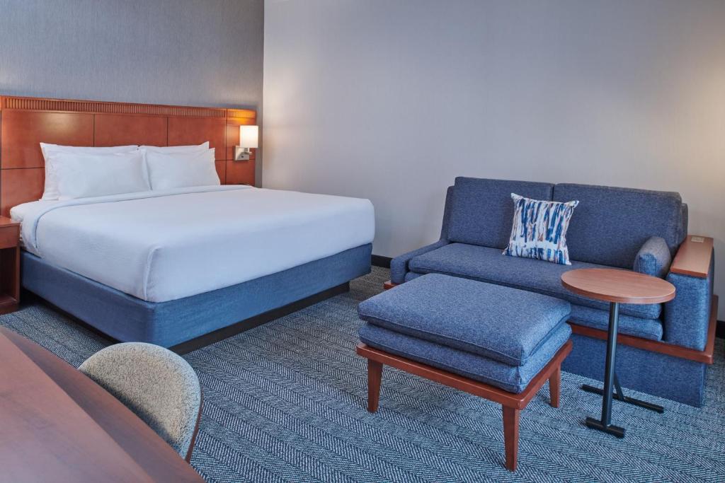 a bedroom with a bed and a couch and a chair at Courtyard by Marriott Detroit Livonia in Livonia
