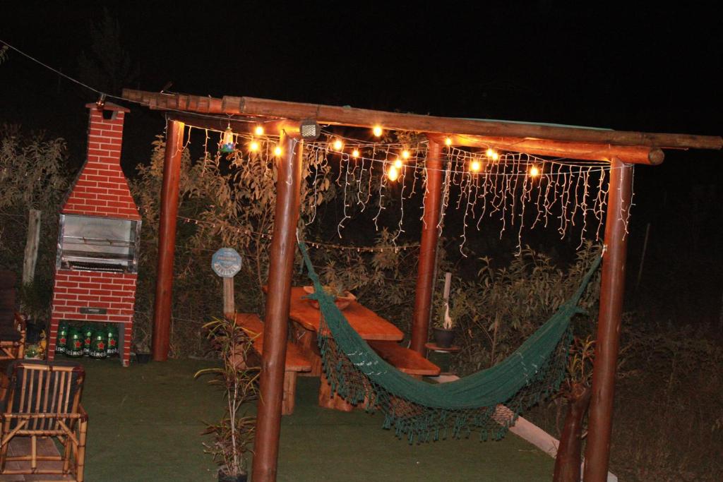 a hammock with lights and a house in the background at Chalé Capão Vibes in Vale do Capao